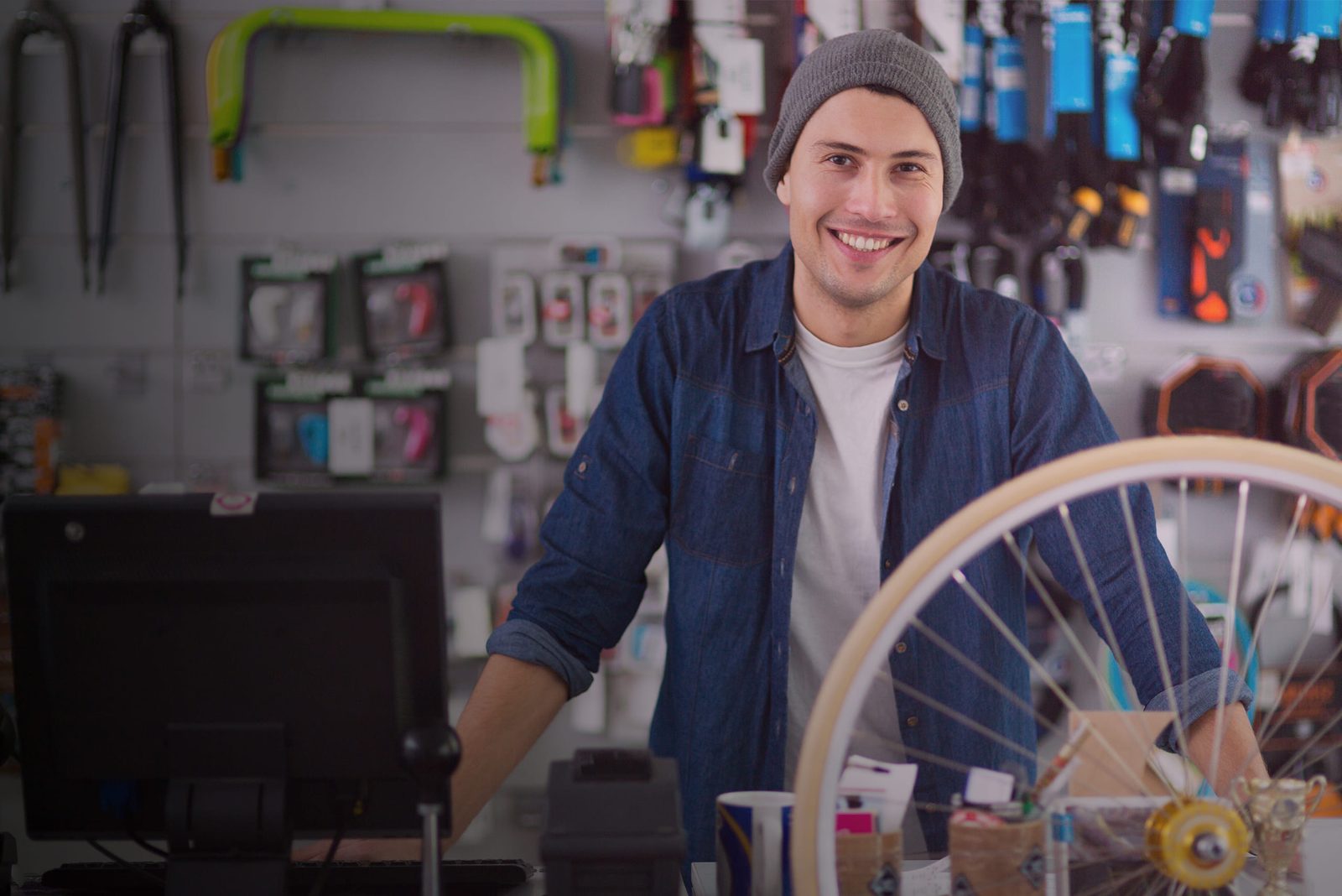 Dueño de una tienda de bicicletas atendiendo detrás de su mostrador, con la terminal de punto de venta a la vista